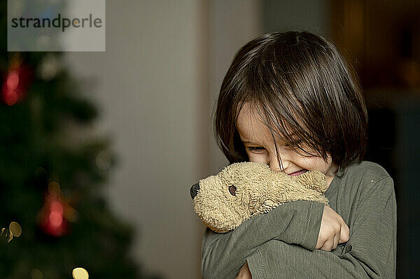 Glücklicher Junge umarmt Spielzeughund zu Hause