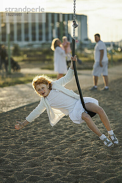 Fröhliches Mädchen genießt und schwingt auf der Schaukel im Park