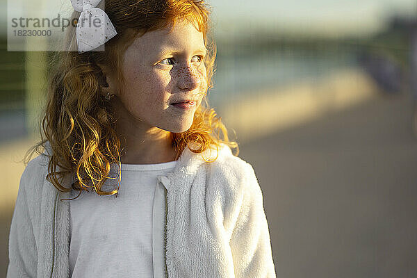 Smiling redhead girl standing outdoors on a sunny day
