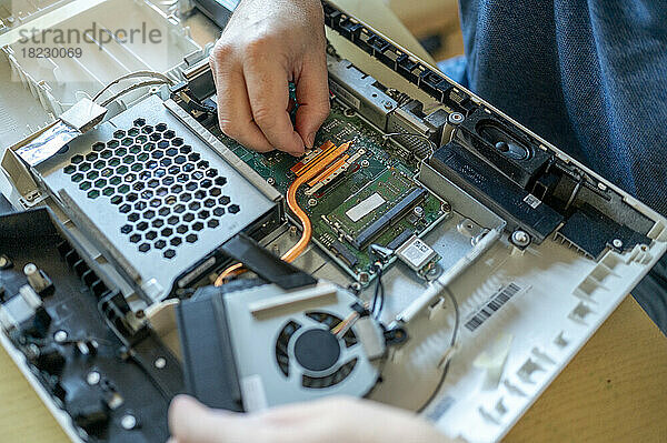 Hände eines Mannes  der einen Computer auf dem Tisch repariert