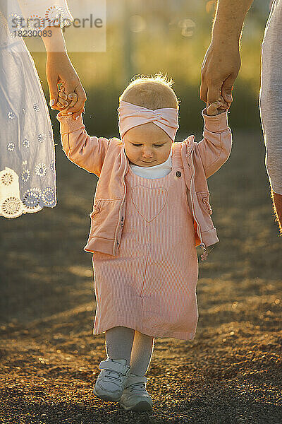 Nettes kleines Mädchen hält Händchen und geht mit den Eltern spazieren