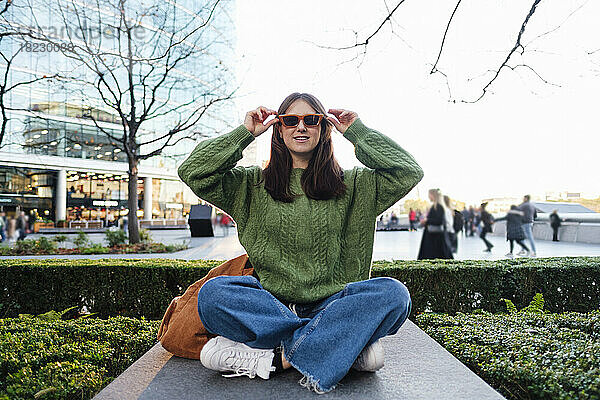 Junge Frau mit Sonnenbrille auf Betonsitz