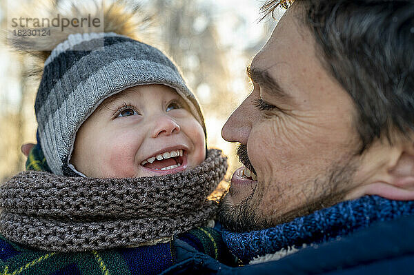 Glücklicher Mann mit Sohn  der im Winter warme Kleidung trägt