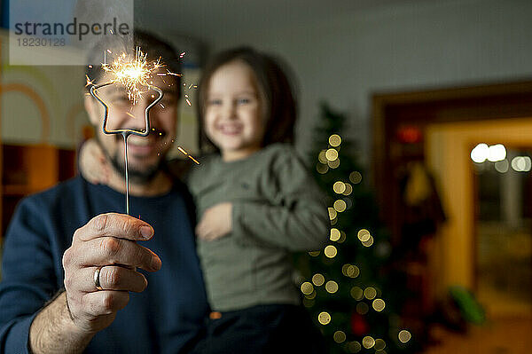 Vater und Sohn halten zu Hause Wunderkerze in der Hand