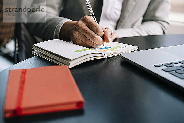 Geschäftsfrau schreibt Tagebuch mit Stift am Tisch im Café