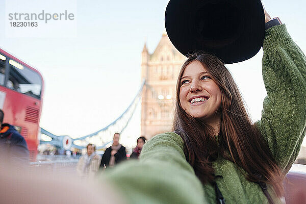 Glückliche junge Frau im grünen Pullover macht ein Selfie auf der Tower Bridge  London  England