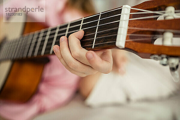 Hand of girl playing guitar at home
