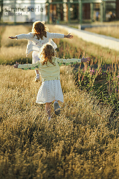 Glückliche Mädchen mit ausgestreckten Armen  die auf Gras laufen