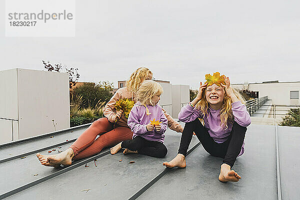 Glückliche Familie genießt zusammen mit Herbstblättern auf dem Dach