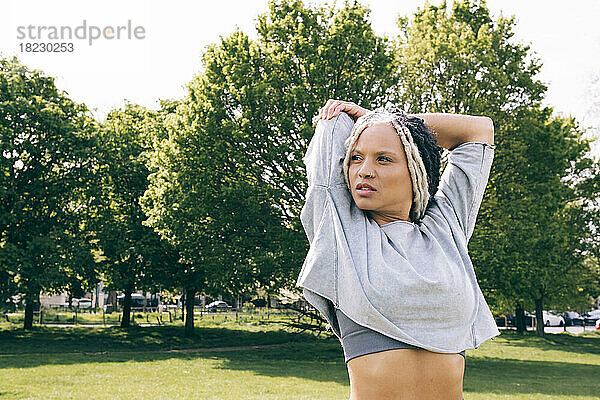 Nachdenkliche Frau beim Stretching im Park