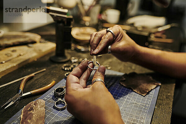 Hände einer Handwerkerin reparieren Ring an der Werkbank