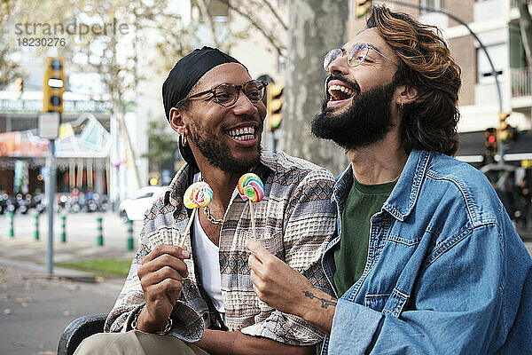 Glückliches schwules Paar genießt Süßigkeiten auf einer Bank