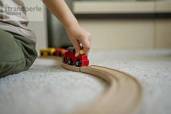 Hand of boy playing with wooden toy train at home