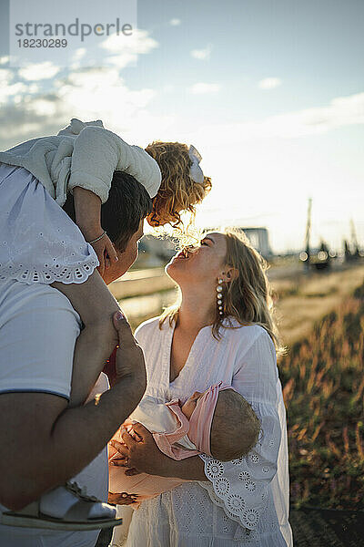 Glückliche Mutter und Vater genießen es mit ihren Töchtern an einem sonnigen Tag