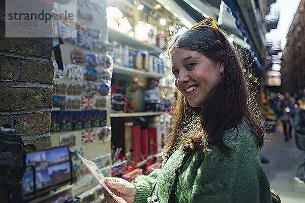 Lächelnde junge Frau kauft Souvenirs im Geschäft