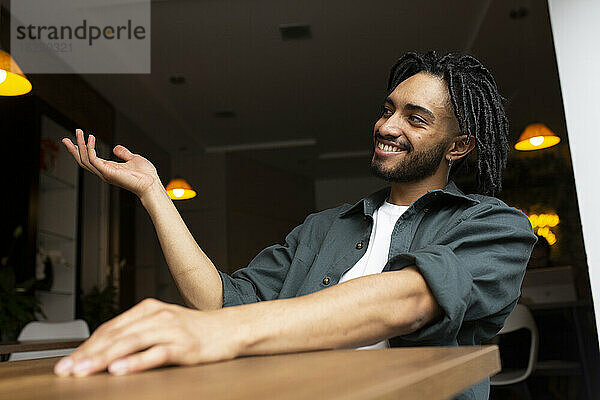 Smiling man gesturing sitting at table in home