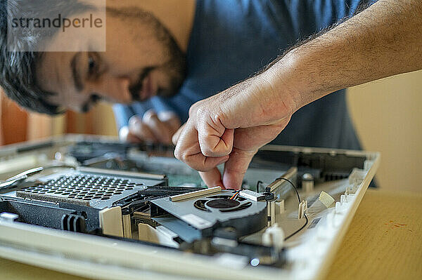 Mann repariert Hauptplatine des Computers auf dem Tisch zu Hause