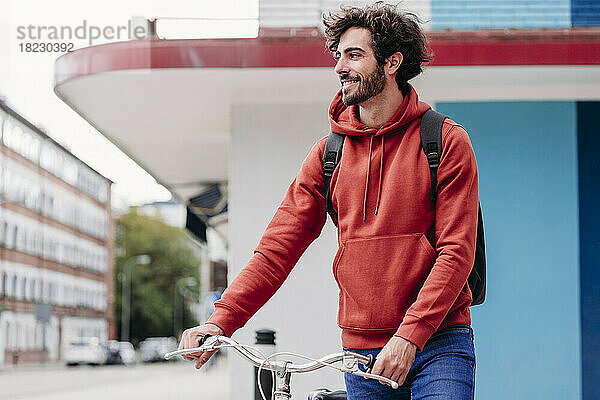 Lächelnder Mann überquert Straße mit Fahrrad