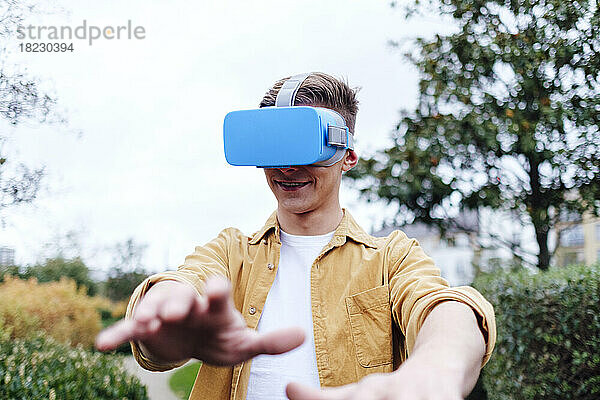 Lächelnder junger Mann mit Virtual-Reality-Headset