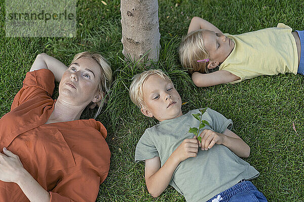 Mother with son and daughter lying down on grass