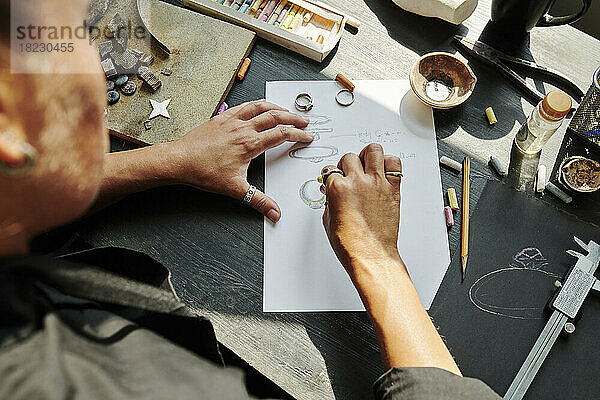 Juwelier skizziert Ringdesign auf Papier an der Werkbank