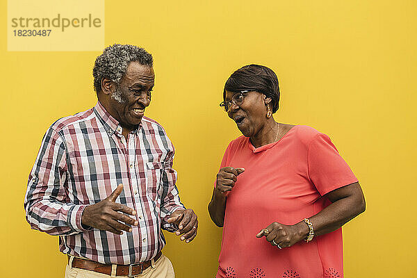 Glückliches älteres Paar tanzt vor gelbem Hintergrund