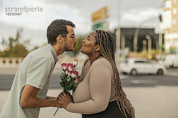 Junges Paar kräuselt sich mit Blumenstrauß am Fußweg