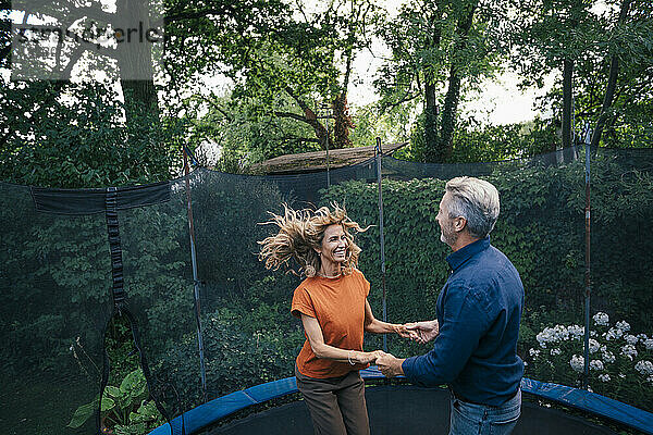 Cheerful man and woman jumping on trampoline