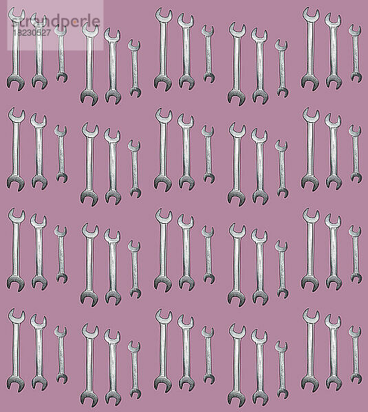 Muster aus Schraubenschlüsselreihen flach auf rosa Hintergrund gelegt