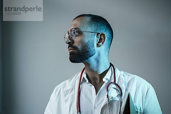 Doctor with stethoscope in front of wall