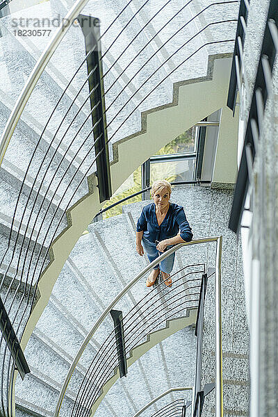 Reife Geschäftsfrau steht auf der Treppe am Arbeitsplatz