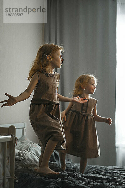 Glückliche Geschwister springen und tanzen zu Hause auf dem Bett