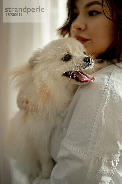 Schöne junge Frau mit Pommerschen Hund zu Hause