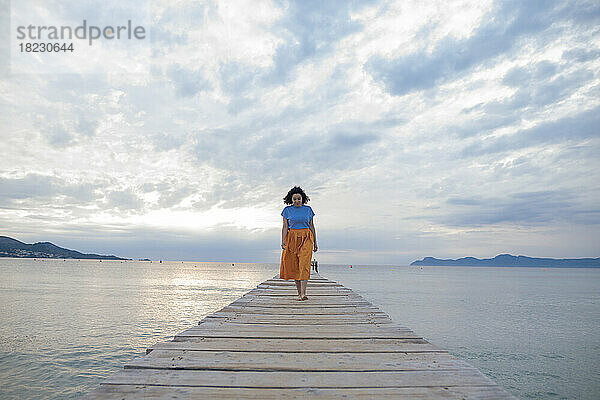 Woman walking on jetty amidst sea