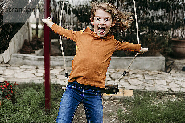 Playful girl jumping from swing in garden