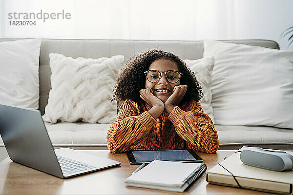 Glückliches Mädchen mit Brille sitzt zu Hause im Wohnzimmer