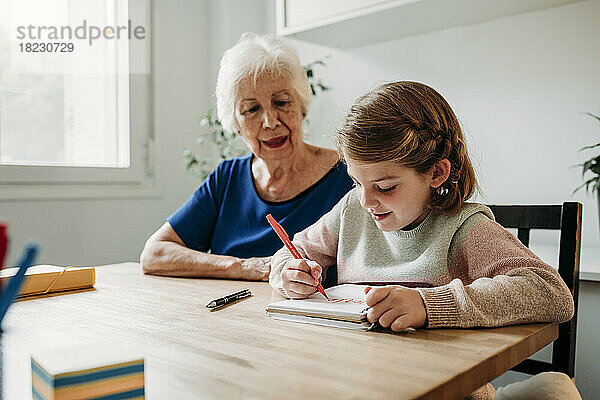 Großmutter hilft Mädchen beim Lernen am Tisch zu Hause
