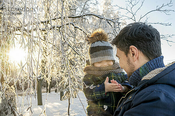 Glücklicher Mann hält Sohn im Winterpark