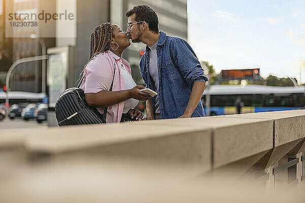Junges Paar küsst sich vor dem Gebäude