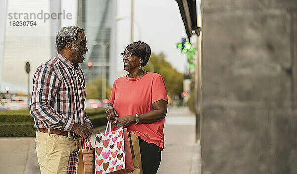 Älteres Paar mit Einkaufstüten redet miteinander