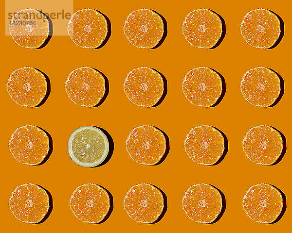 Muster aus halbierten Mandarinen mit einer einzelnen Zitrone in der Mitte