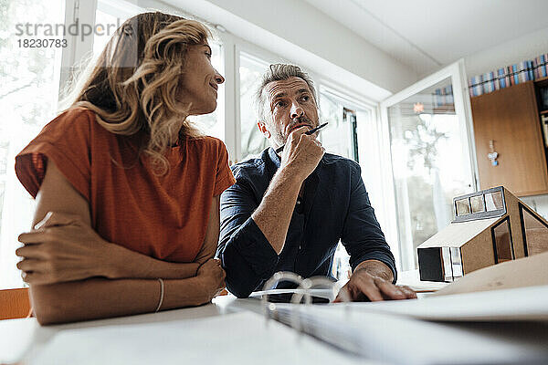 Reifer Mann und Frau diskutieren am Tisch über einen Immobilienvertrag