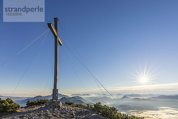 Deutschland  Bayern  Gipfelkreuz des Herzogstandes mit aufgehender Sonne im Hintergrund