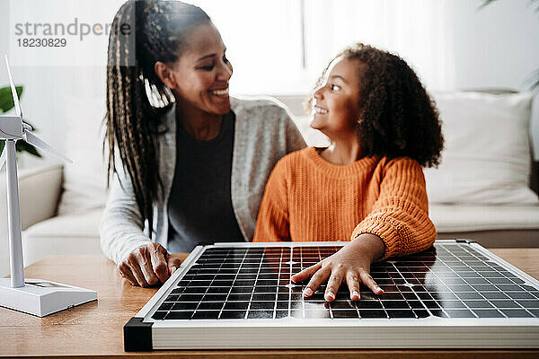 Glückliche Mutter und Tochter mit Solarpanel zu Hause