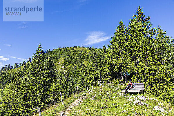 Germany  Bavaria  Female hiker relaxing on mountaintop bench