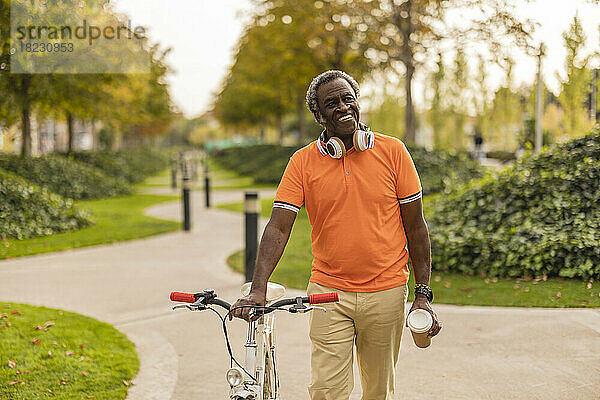 Lächelnder älterer Mann  der im Park Fahrrad fährt