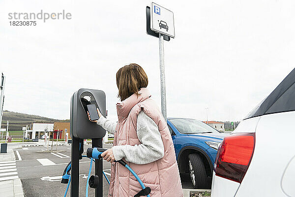 Frau scannt Smartphone an Ladestation