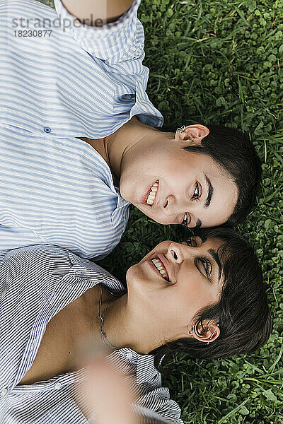 Lächelndes lesbisches Paar  das einander im Gras anschaut