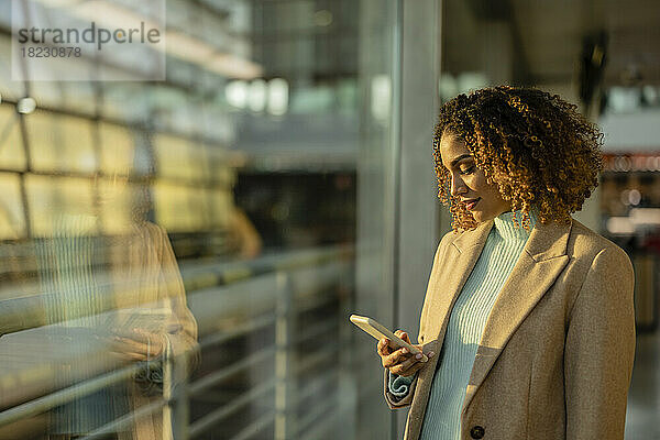 Frau benutzt Mobiltelefon im Bahnhof