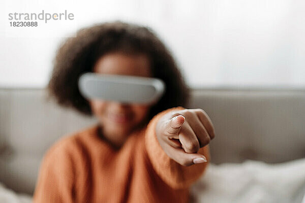 Mädchen mit Virtual-Reality-Simulator gestikuliert zu Hause